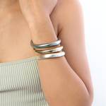 Woman wearing multiple bracelets on a light background